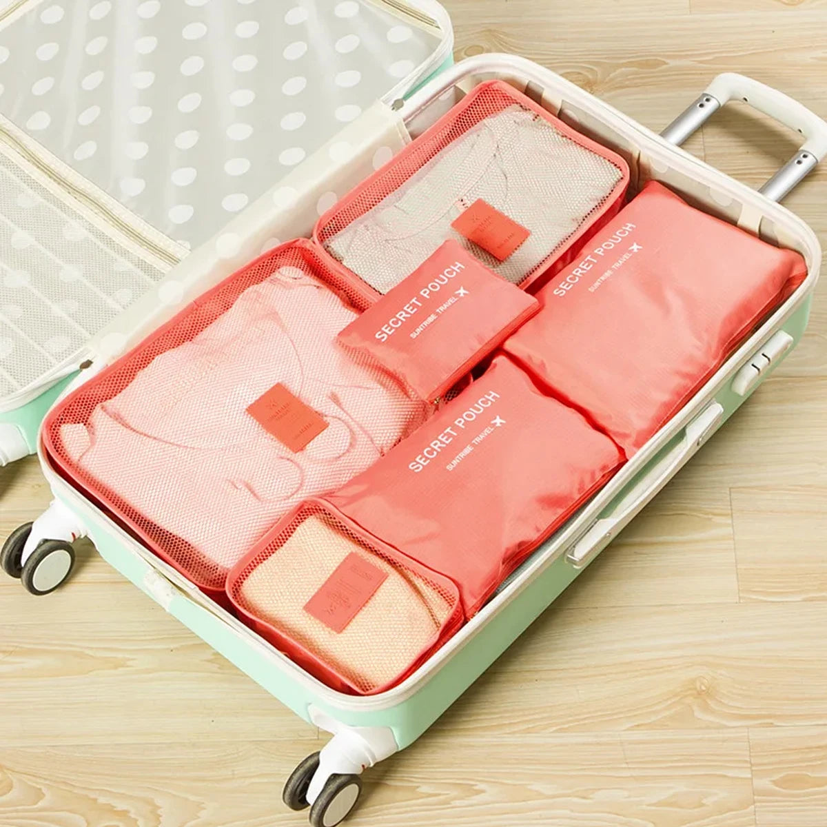 A light green travel organizer storage set with six pink and beige pouches inside.