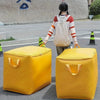 A person is standing next to two large yellow storage bags on a sidewalk.