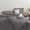 A black and white plaid duvet cover set with ruffled edges is displayed on a bed.
