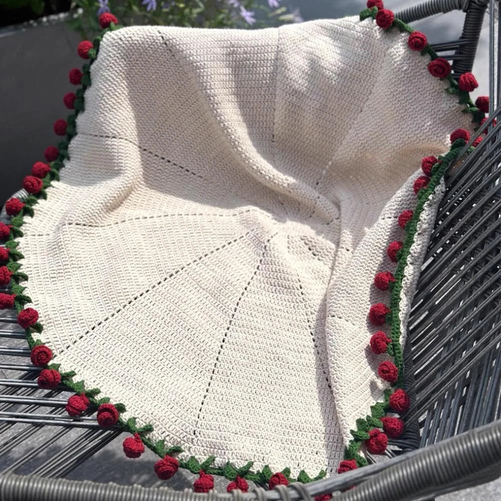 Handmade rose crochet blanket displayed in a black wire basket