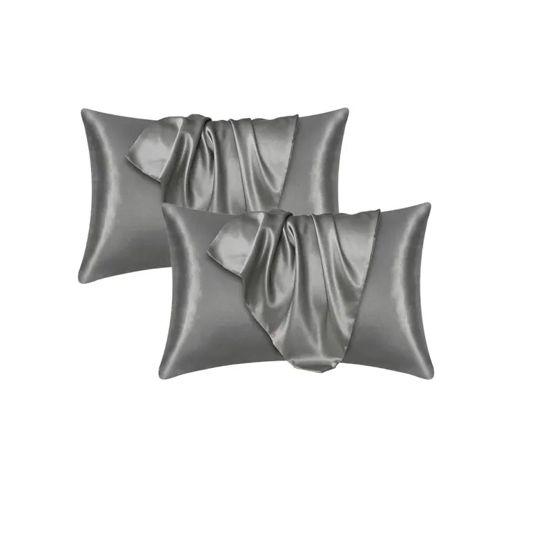 Three satin silk pillow covers in a gray color folded and displayed
