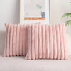 A pink faux rabbit fur cushion cover is displayed on a light-colored sofa next to a framed picture.