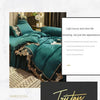A luxurious emerald green bed skirt set with gold lace edging and sheer fabric, shown in a bedroom setting.