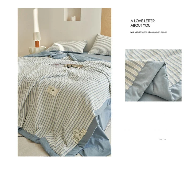 A light blue and white striped luxury jacquard summer quilt draped on a bed.