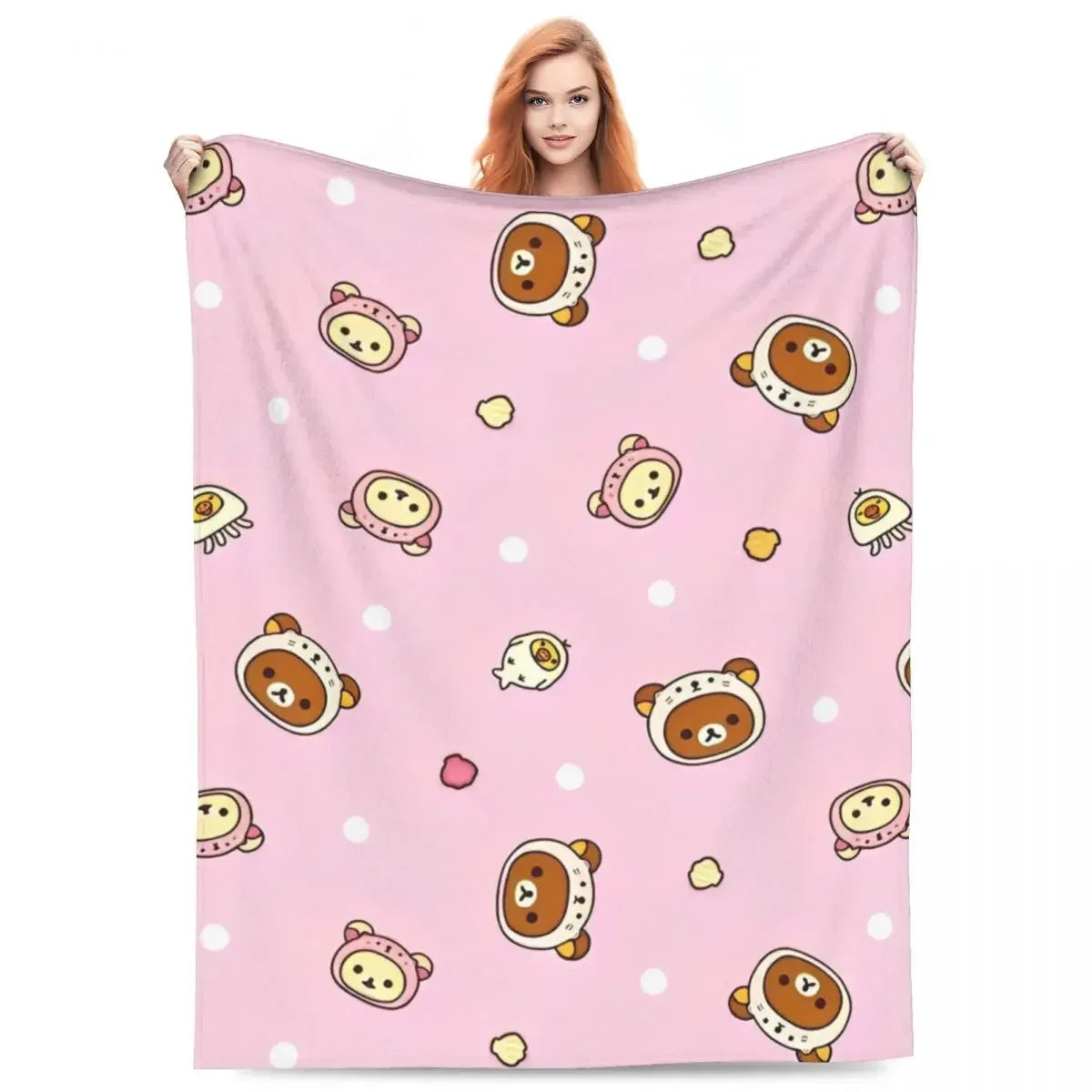 A pink throw blanket featuring a pattern of cute cartoon bears and white polka dots.