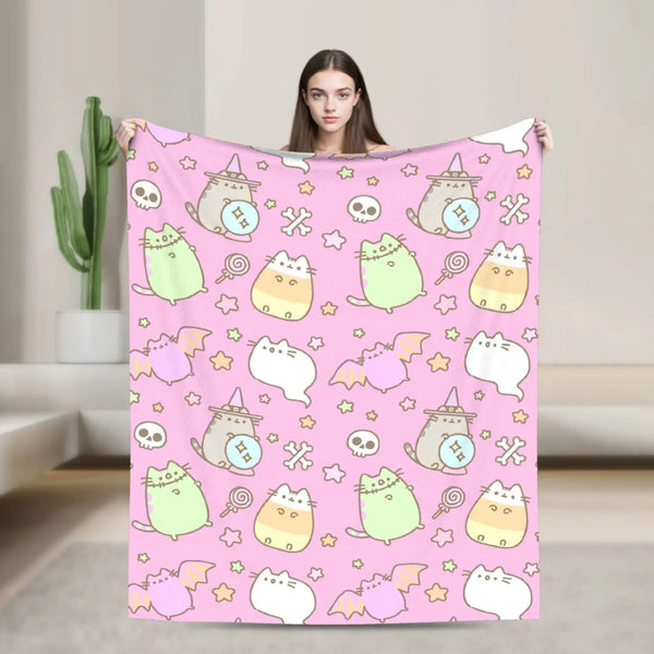 A person is modeling a pink cat plush throw blanket featuring various cute cats and skulls against a light background.