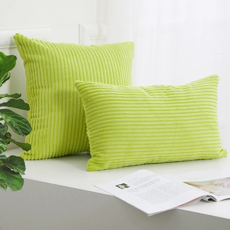 A stack of bright lime green corduroy striped throw pillows resting on a white surface.