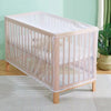 A light pink portable mosquito net crib with vertical slats and a sheer fabric covering is shown on a light-colored rug.
