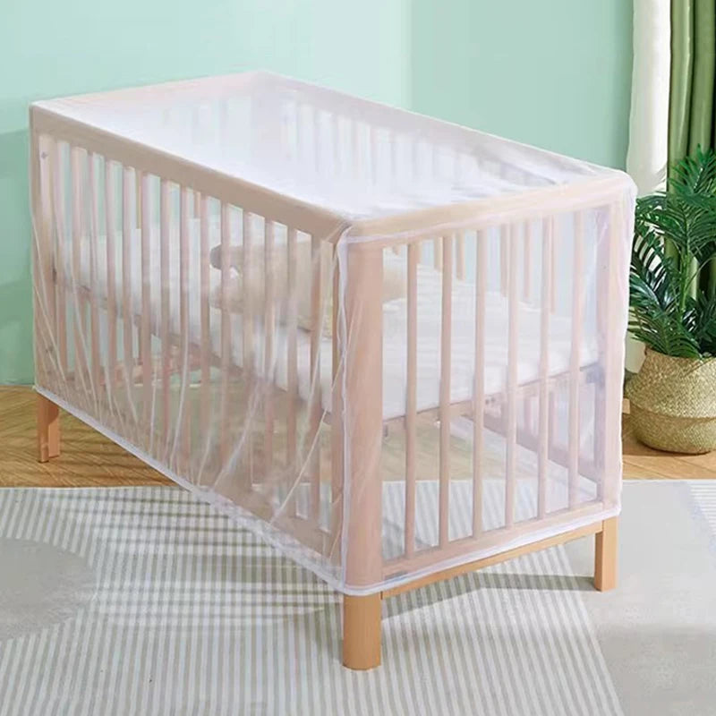 A light pink portable mosquito net crib with vertical slats and a sheer fabric covering is shown on a light-colored rug.