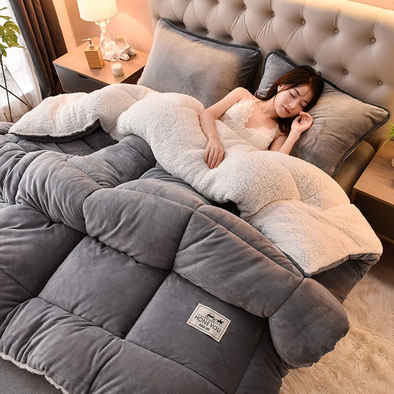 A woman is relaxing on a large, plush gray fleece blanket in a bedroom setting.