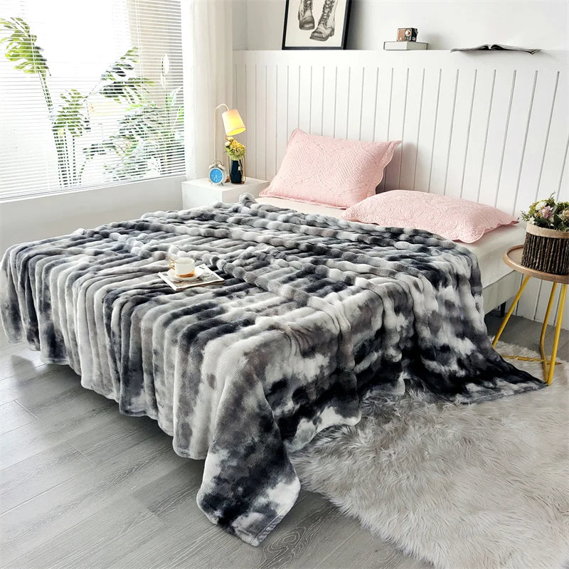 A gray and black plush rabbit fur throw blanket draped over a white sofa in a bright room.
