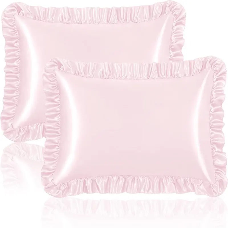 A set of two ruffled satin pillowcases in a light pink color with silky envelope closures.