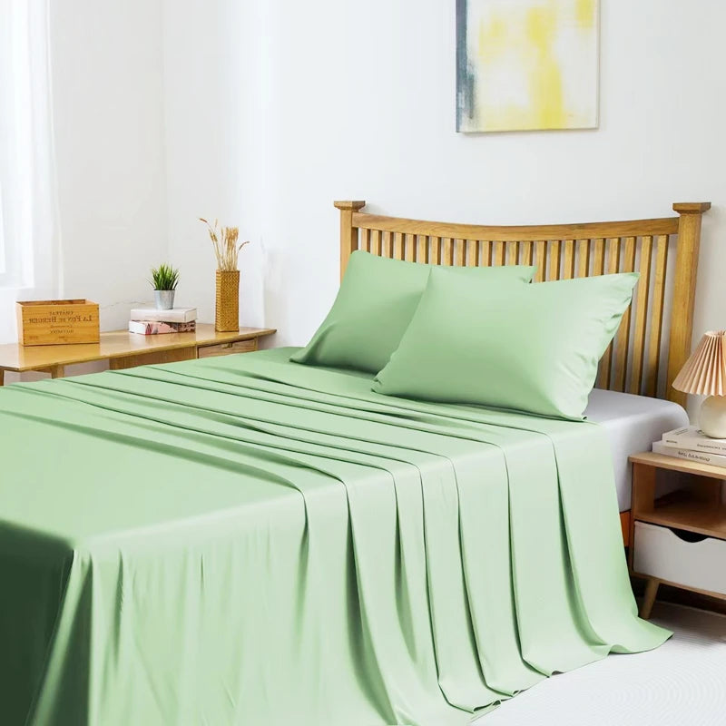 A light green bamboo fiber flat bed sheet draped over a wooden bed frame in a bright bedroom setting.