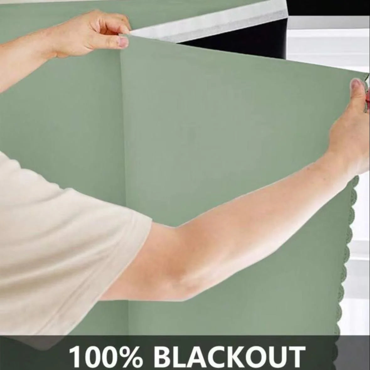 A person is holding a section of a light green blackout curtain fabric to show its texture and drape.