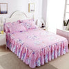 A pink floral printed bed skirt on a white wooden bed with a headboard and bedside table.