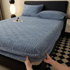 A light blue plush jacquard mattress cover is shown on a bed, with a black headboard and a black and white patterned floor.