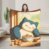 A plush decorative throw blanket featuring a cartoon panda sleeping happily on a wooden table.
