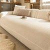 A beige stripe chenille sofa cover displayed on a light-colored sofa with natural wood accents and sheer curtains.