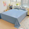 Light blue floral printed bedding set with white pillows and a matching blue bedspread on a wooden floor.