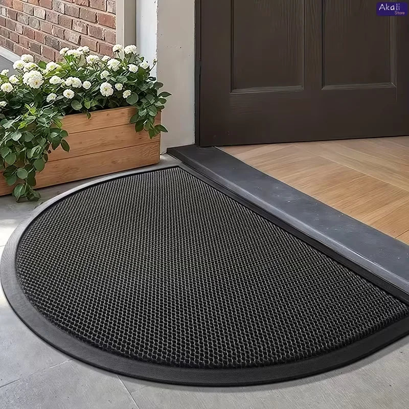 A half-round non-slip PVC door mat with a black mesh surface placed on a light gray floor.