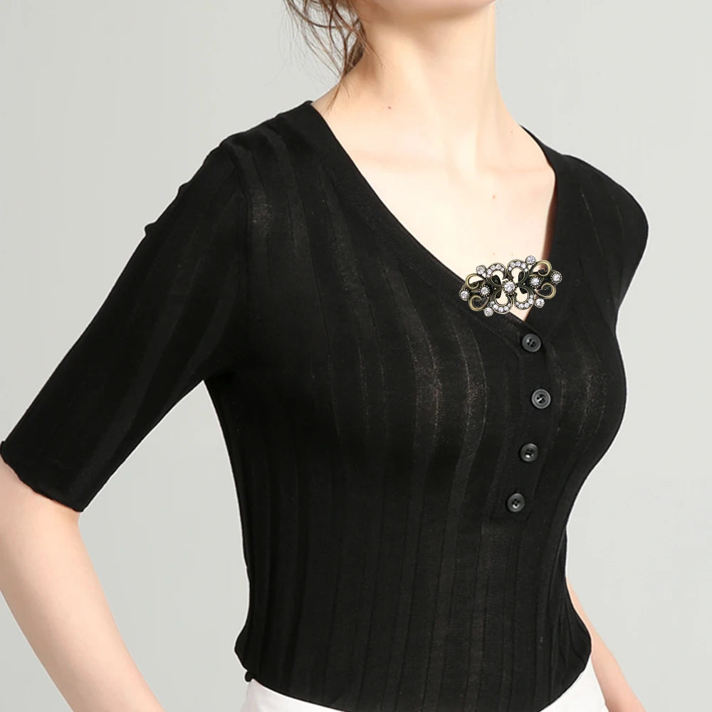 Black ribbed top with a silver clip brooch worn by a model.