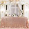 A pink sequin glitter tablecloth set up for a wedding or party display with white flowers and candelabras.