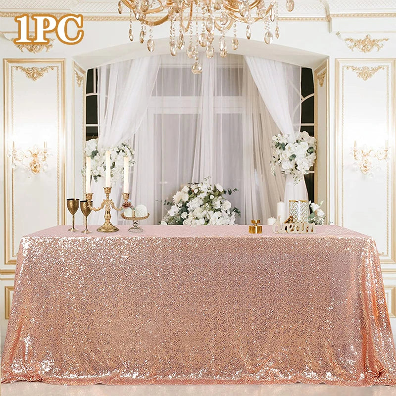 A pink sequin glitter tablecloth set up for a wedding or party display with white flowers and candelabras.