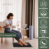 A woman sits on a mat indoors using a 15 ft grounding cord for wellness.