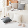 A sofa cover featuring light beige, gray, and white throw pillows on a white couch.