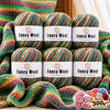 A set of six balls of fancy wool yarn in various gradient colors stacked on a surface.