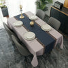 A long rectangular table set for dining or party decor with a gray tablecloth, white plates, and gold candlesticks.