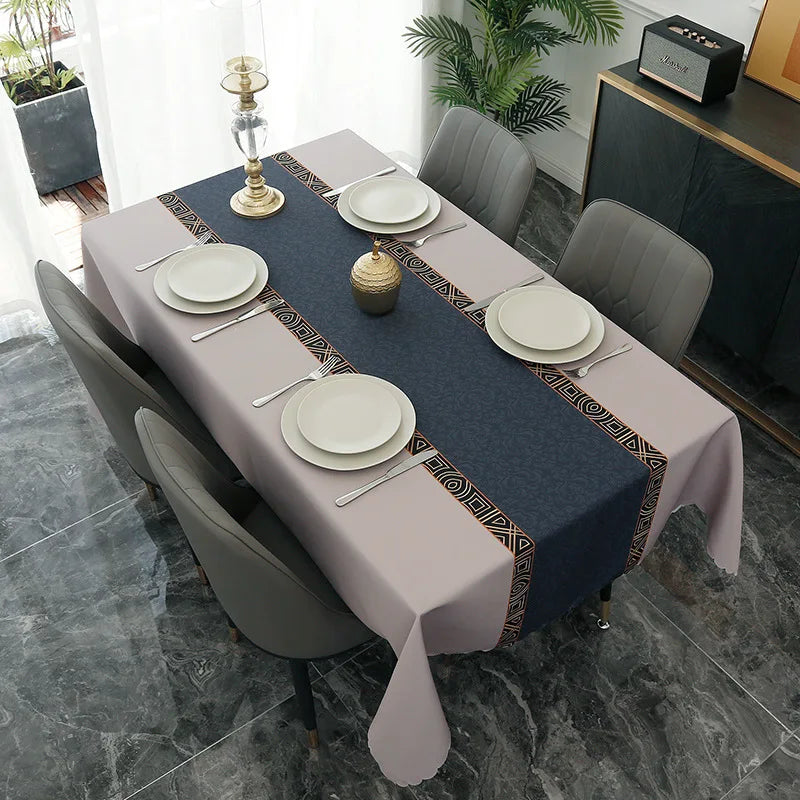 A long rectangular table set for dining or party decor with a gray tablecloth, white plates, and gold candlesticks.