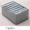 A gray foldable drawer organizer with seven fabric dividers for storing undergarments and accessories.