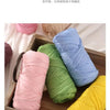 A wooden tray filled with colorful elastic yarn in pink, green, blue, and yellow.