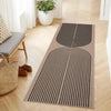 A long runner rug with black and beige geometric lines laid on a light wood floor.