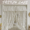 White sheer French lace curtains with delicate ruffles framing a bedroom window.