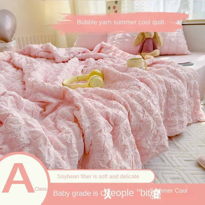 Pink bubble yarn summer cool quilt with a stuffed animal on a bed