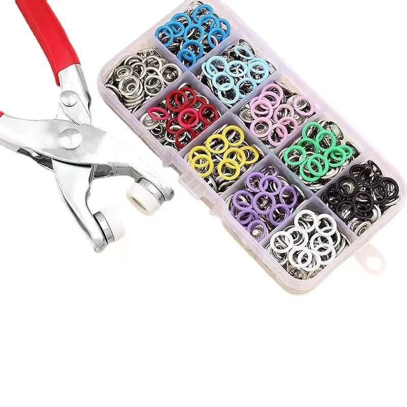 A plastic case filled with various colorful metal sewing buttons and a pair of silver sewing scissors.