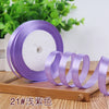 Purple satin ribbon roll with several unrolled ribbons displayed on a wooden surface.