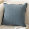 A square, textured gray chenille throw pillow cover resting on a light beige sofa.