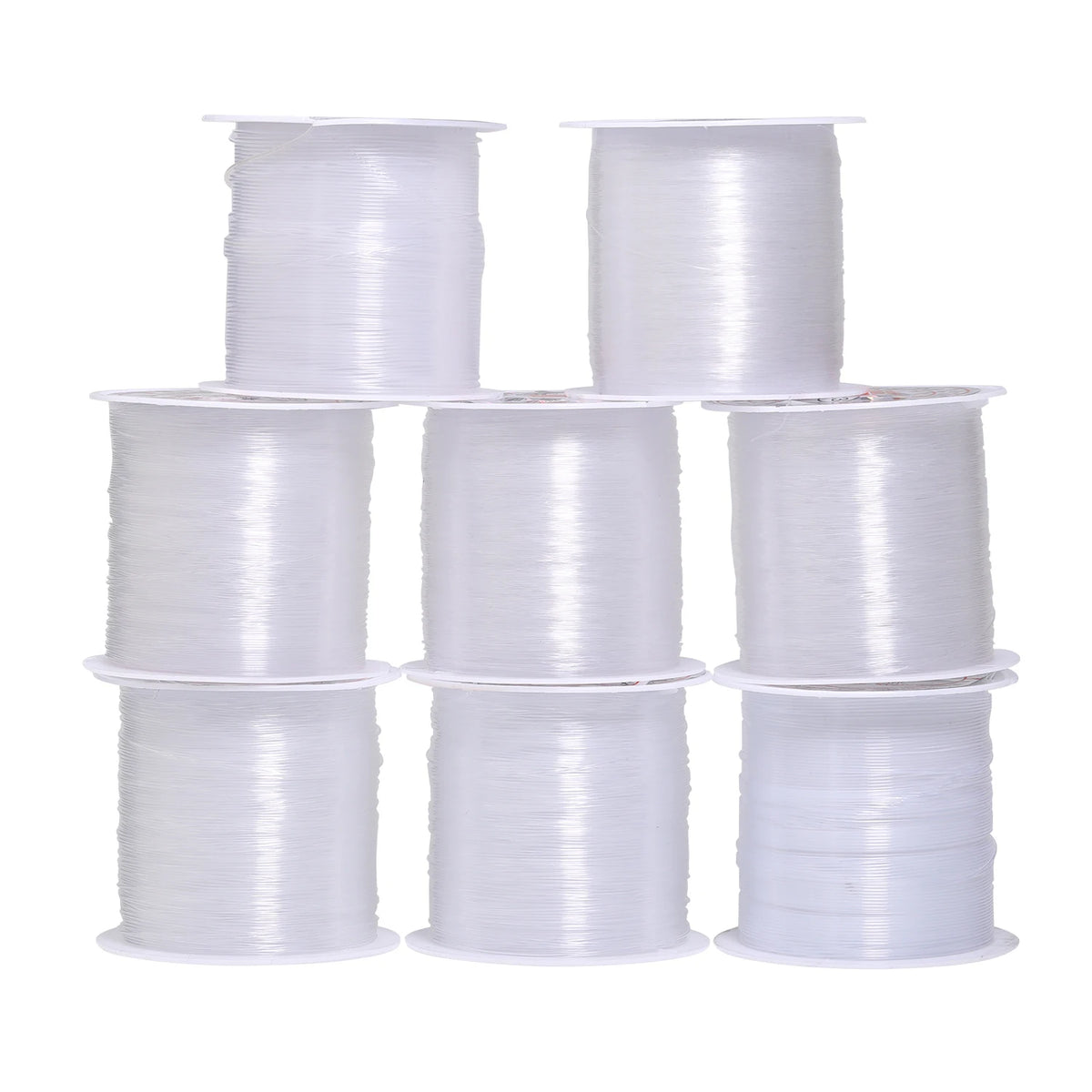 A collection of white precision nylon beading thread spools in various sizes.