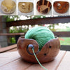 A wooden bowl filled with bright green yarn, used for crochet and knitting organization.