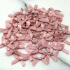 A collection of small pink satin ribbon bows for crafts and decor laid out on a white marble surface.