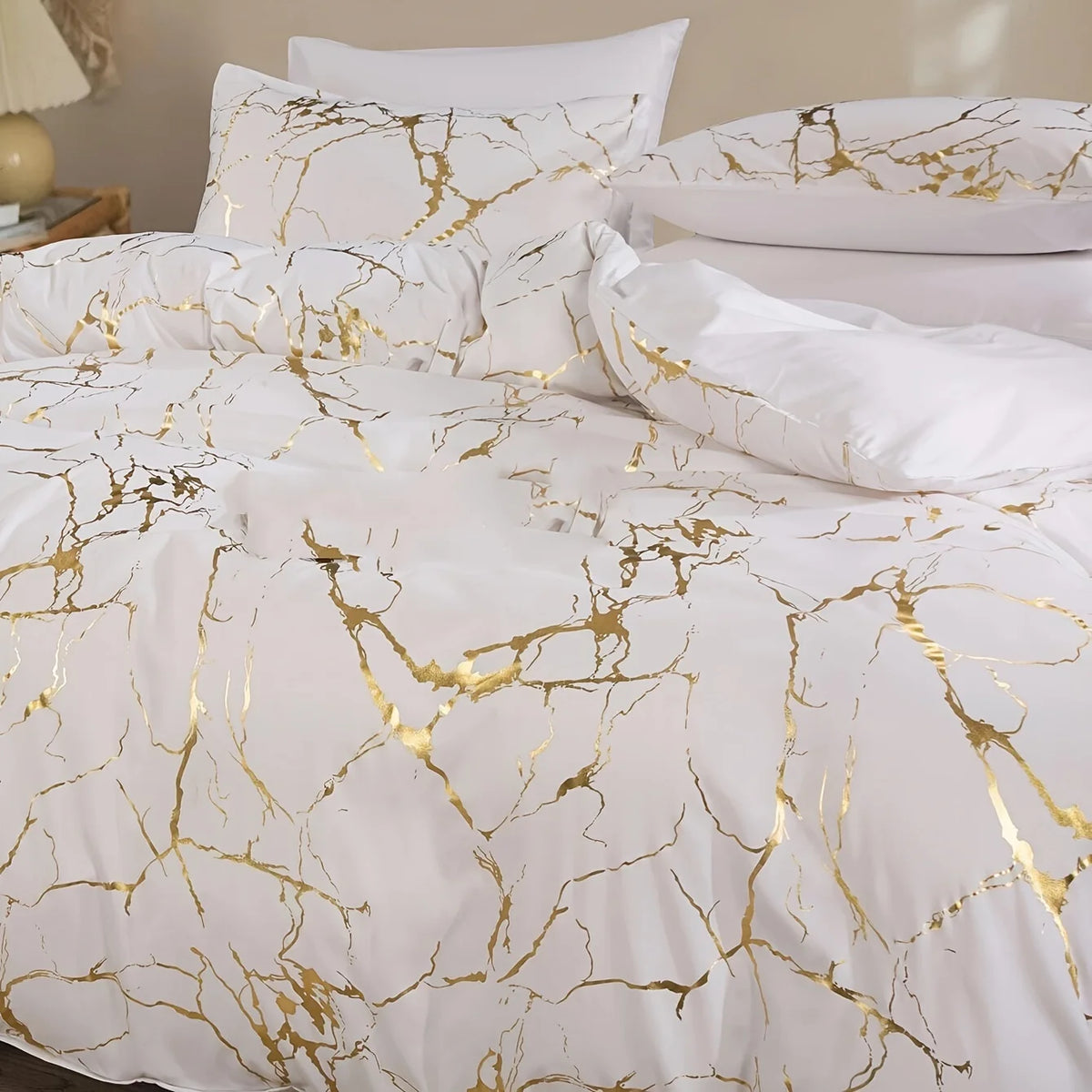 White duvet cover set with gold marble print featuring pillows and bedding.