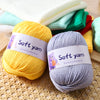 A stack of soft yellow and gray hand knitting yarn skeins resting on a woven mat.