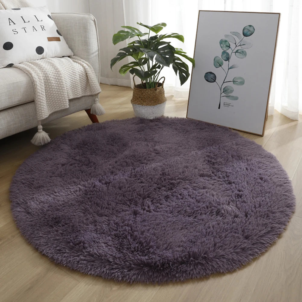 A round, dark purple shaggy area rug placed on a light wooden floor next to a sofa and a potted plant.