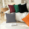 A collection of colorful and textured lumbar support pillows on a white bed with a white blanket.