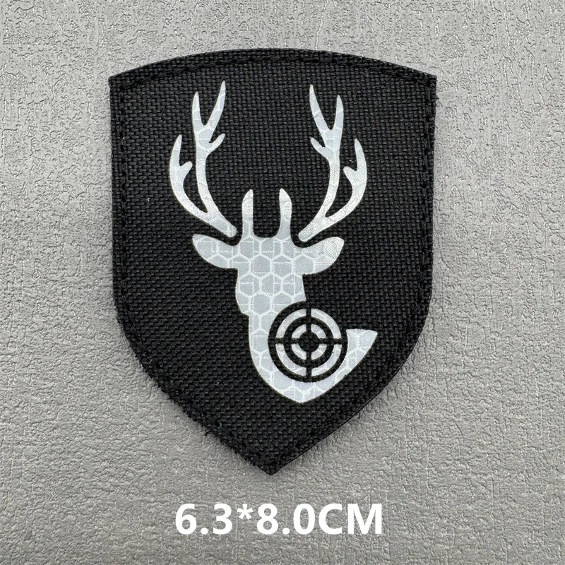A black shield-shaped patch featuring a white deer antler silhouette with a crosshair design.