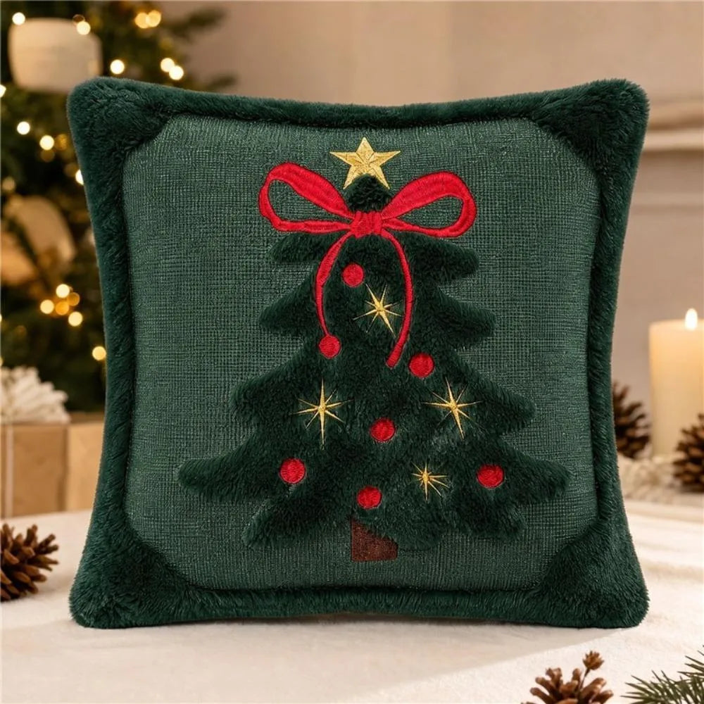 A dark green velvet embroidered pillow featuring a festive Christmas tree with red ribbon and gold stars.