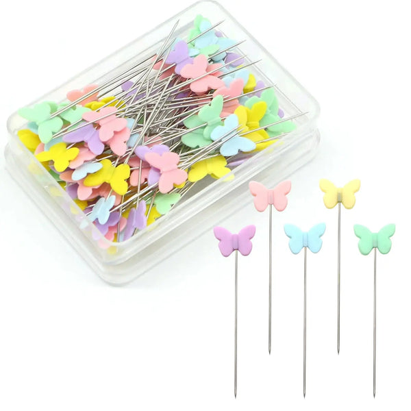 A clear plastic container filled with a bulk set of colorful sewing pins shaped like butterflies for crafting